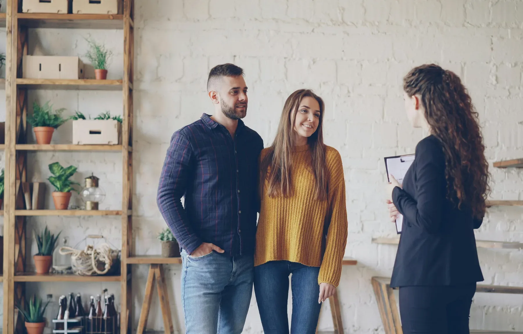 A real estate agent presents a property to a young couple interested in purchasing their new home.
