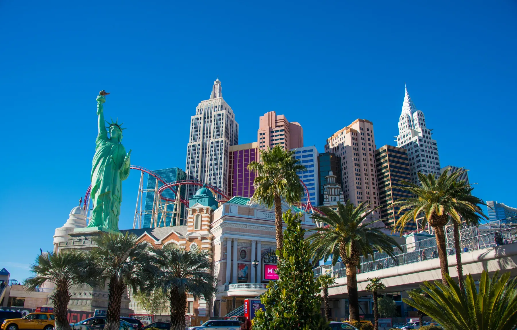 Vibrant Las Vegas cityscape featuring the New York-New York Hotel & Casino with replica Statue of Liberty, palm trees, and mo